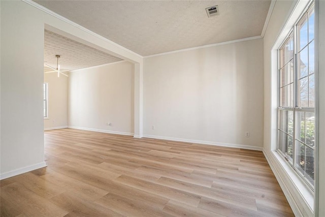 spare room with a wealth of natural light, light wood-style flooring, and ornamental molding