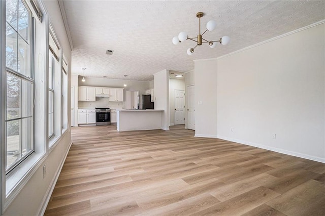 unfurnished living room with light wood-type flooring, a notable chandelier, a textured ceiling, crown molding, and baseboards