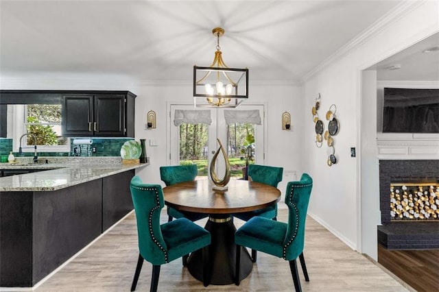 dining area with crown molding, a brick fireplace, light wood-type flooring, and a wealth of natural light