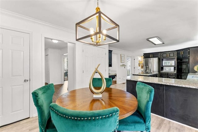 dining room with crown molding, light wood-style floors, and a chandelier