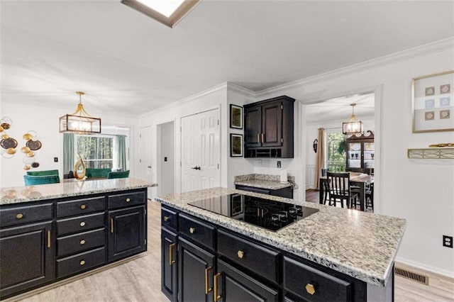 kitchen with visible vents, a center island, black electric cooktop, and dark cabinets