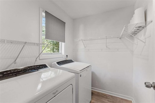 washroom featuring baseboards, wood finished floors, laundry area, and washing machine and clothes dryer