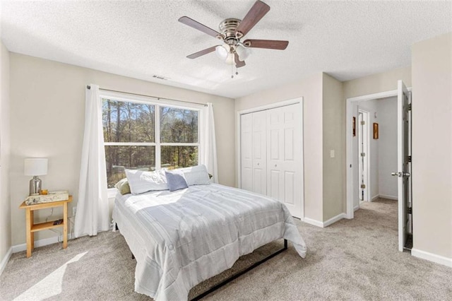 bedroom featuring visible vents, light carpet, a closet, baseboards, and ceiling fan