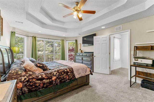 bedroom with a tray ceiling, visible vents, and a textured ceiling