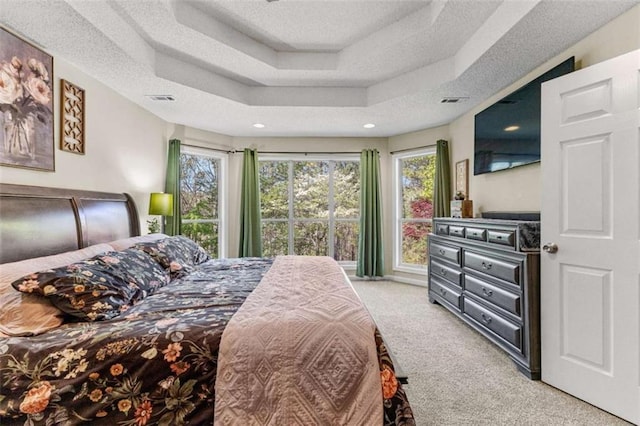 bedroom with visible vents, a raised ceiling, a textured ceiling, and light carpet