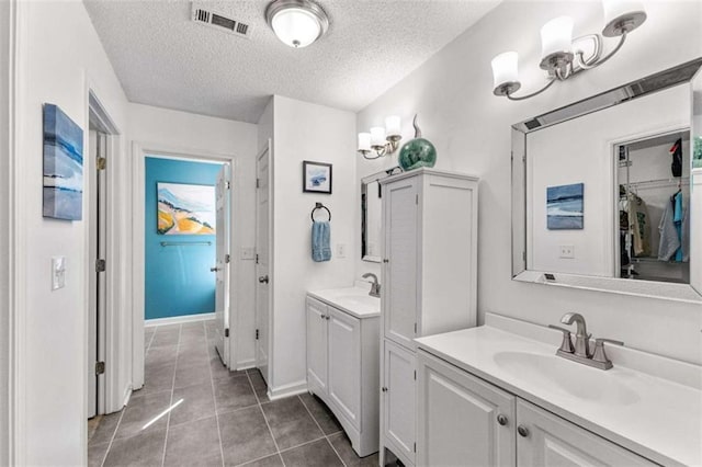 full bath featuring tile patterned flooring, two vanities, visible vents, and a sink