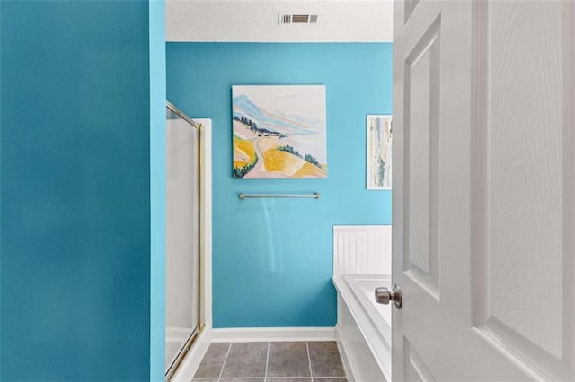 bathroom featuring tile patterned flooring, visible vents, baseboards, a stall shower, and a bath