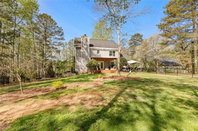 back of house featuring a chimney, a yard, and fence