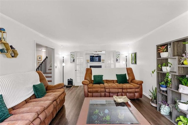 living room with stairway, a fireplace, wood finished floors, and crown molding