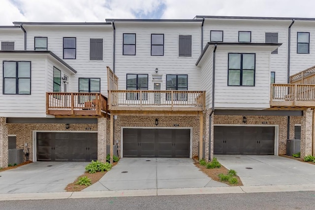 1117 Larkin Dr, Buford, GA 30518 - rear view of house featuring a garage, driveway, brick siding, and central AC unit