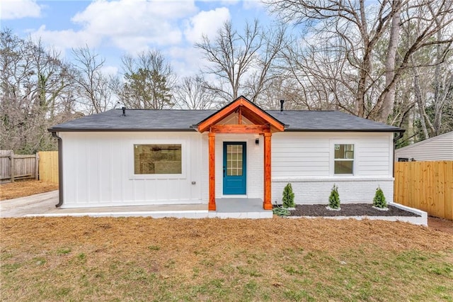 view of front of property with brick siding, a front lawn, and fence