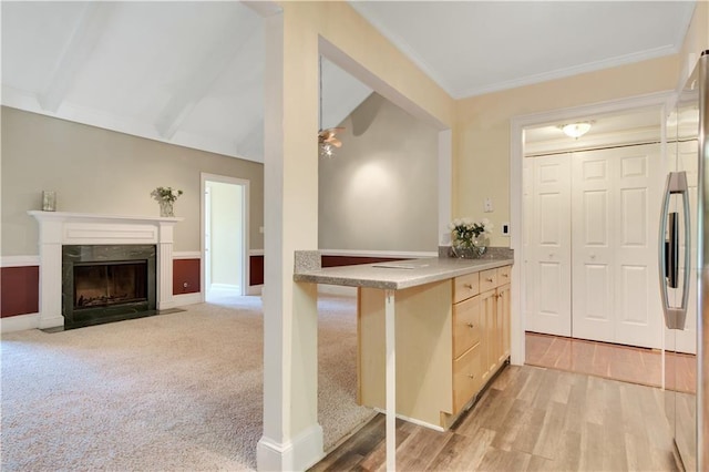 kitchen featuring light brown cabinetry, stainless steel refrigerator, lofted ceiling with beams, light wood-style floors, and a fireplace