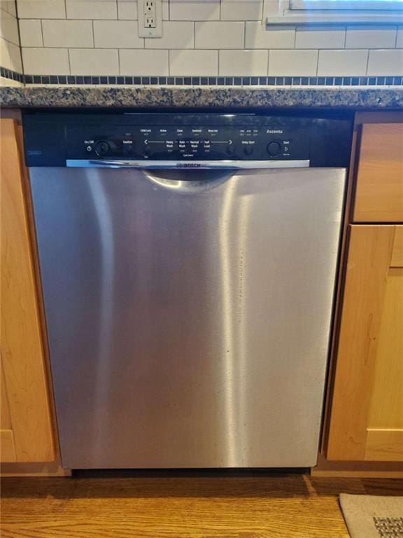 details featuring stainless steel dishwasher, dark countertops, and light wood finished floors