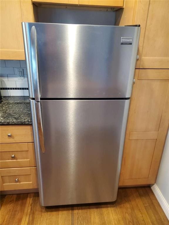 details featuring dark stone counters, light wood finished floors, backsplash, and freestanding refrigerator