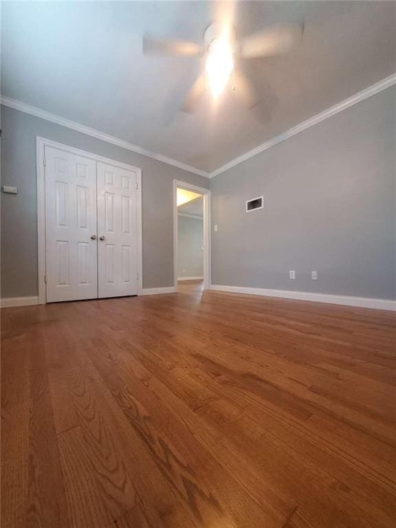 unfurnished bedroom with visible vents, ornamental molding, baseboards, and wood finished floors