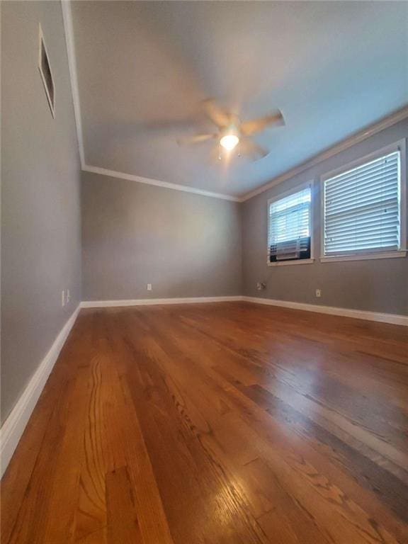 spare room with wood finished floors, baseboards, and ornamental molding