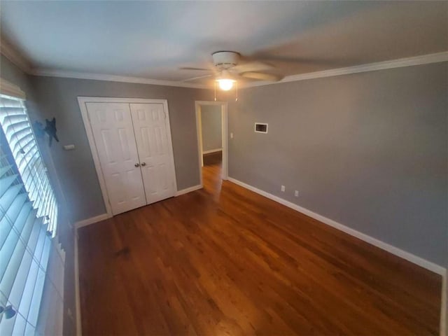 unfurnished bedroom featuring visible vents, ornamental molding, wood finished floors, a closet, and baseboards