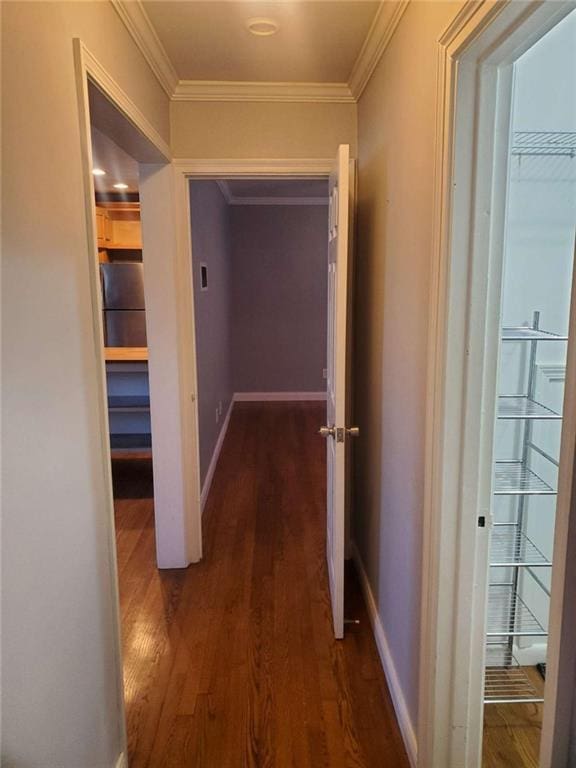 hall with dark wood-type flooring, baseboards, and ornamental molding