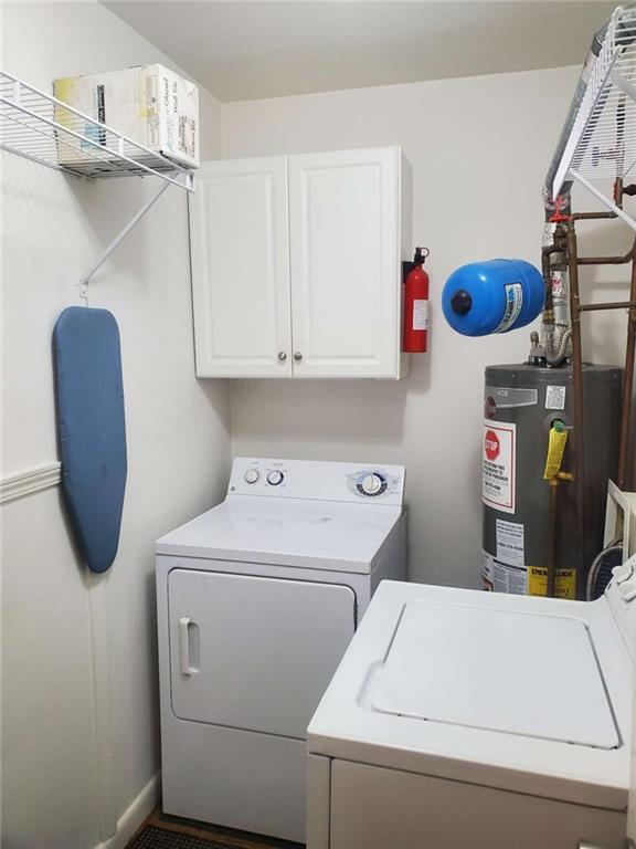 laundry room featuring washer and clothes dryer, gas water heater, and cabinet space