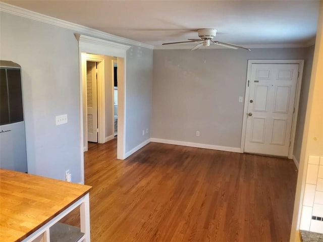 interior space featuring baseboards, a ceiling fan, wood finished floors, and crown molding