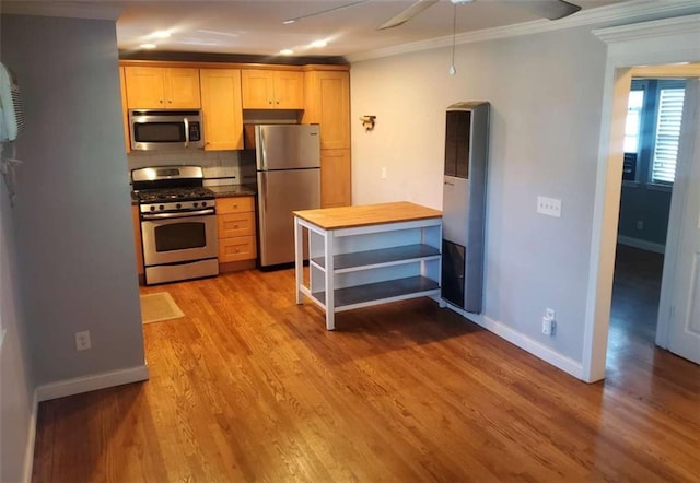 kitchen featuring crown molding, baseboards, decorative backsplash, light wood-style flooring, and appliances with stainless steel finishes