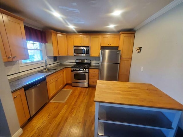 kitchen with light wood-style flooring, a sink, decorative backsplash, butcher block countertops, and appliances with stainless steel finishes