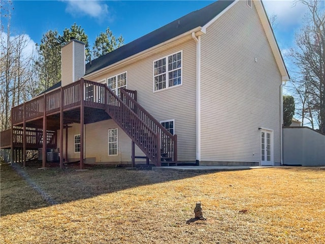 back of property featuring french doors, a wooden deck, and a lawn