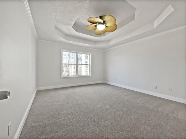 empty room featuring ceiling fan, carpet floors, ornamental molding, a textured ceiling, and a raised ceiling