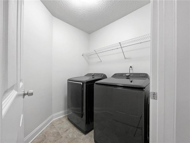 laundry area with washer and clothes dryer and a textured ceiling