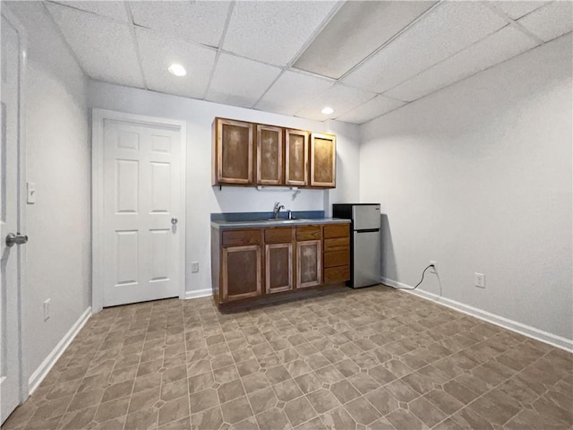 kitchen with stainless steel fridge, sink, and a drop ceiling