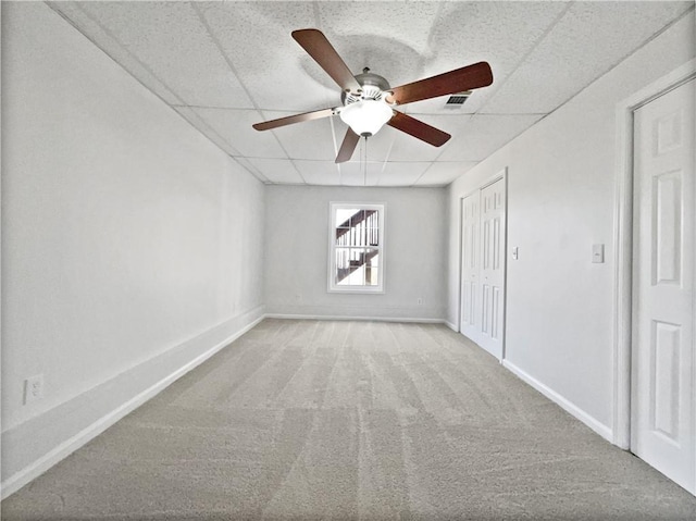 carpeted empty room with a paneled ceiling and ceiling fan