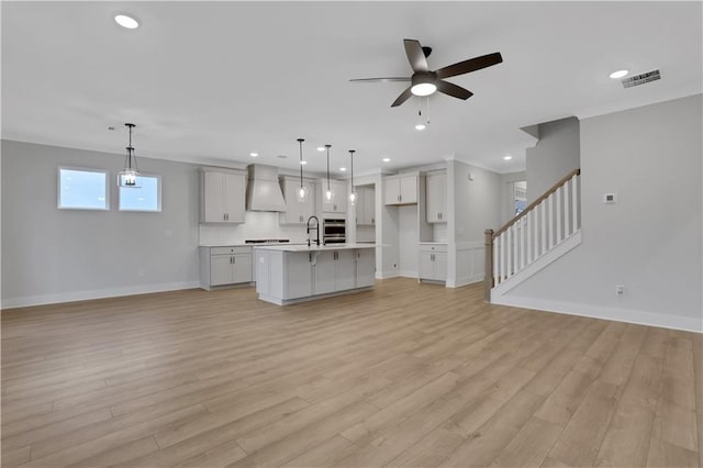 unfurnished living room with ceiling fan, light hardwood / wood-style floors, and sink