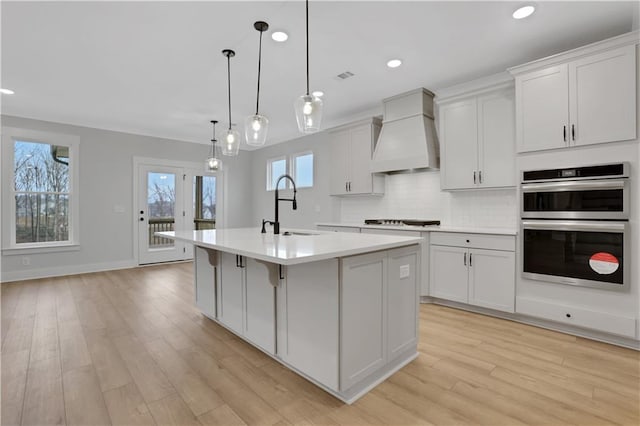 kitchen featuring a center island with sink, decorative light fixtures, a healthy amount of sunlight, and sink