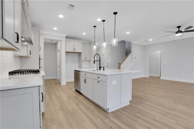 kitchen with light wood-type flooring, white cabinetry, a kitchen island with sink, and sink