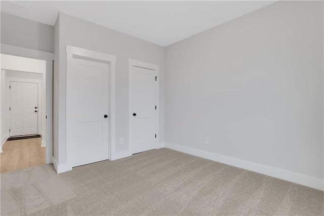 unfurnished bedroom with light colored carpet and a closet