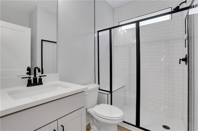 bathroom featuring vanity, a shower with shower door, and toilet