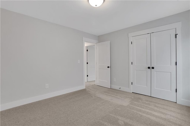 unfurnished bedroom with light colored carpet and a closet