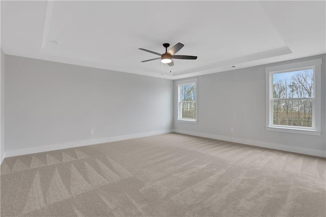 carpeted empty room featuring a tray ceiling and ceiling fan