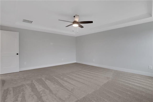 carpeted empty room featuring a tray ceiling and ceiling fan