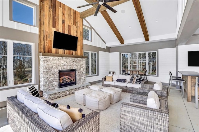 living room featuring a stone fireplace, ceiling fan, beamed ceiling, and high vaulted ceiling