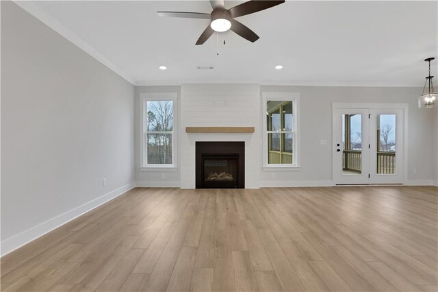 unfurnished living room featuring ceiling fan, crown molding, light wood-type flooring, and a fireplace