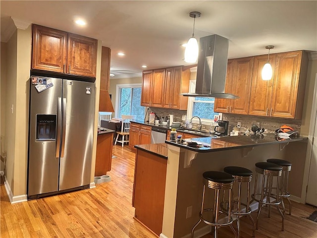 kitchen with kitchen peninsula, island range hood, hanging light fixtures, and appliances with stainless steel finishes