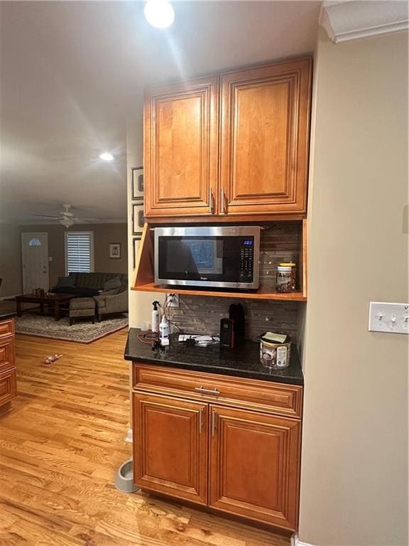 kitchen featuring light hardwood / wood-style floors, decorative backsplash, crown molding, and ceiling fan