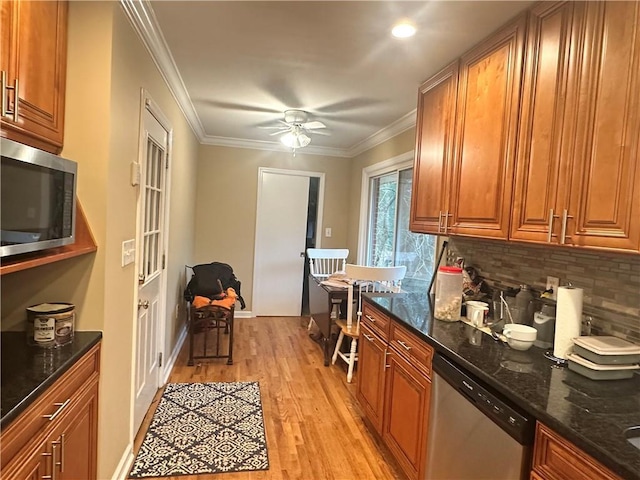 kitchen with stainless steel appliances, dark stone countertops, light hardwood / wood-style flooring, and backsplash