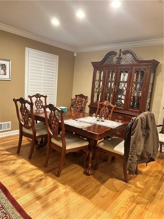 dining space with light wood-type flooring and ornamental molding