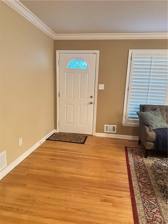 foyer entrance with crown molding and light hardwood / wood-style flooring