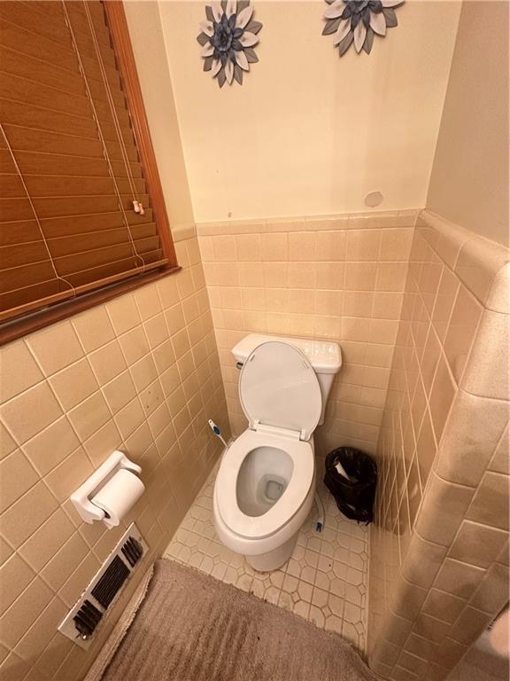 bathroom featuring tile patterned floors, toilet, and tile walls