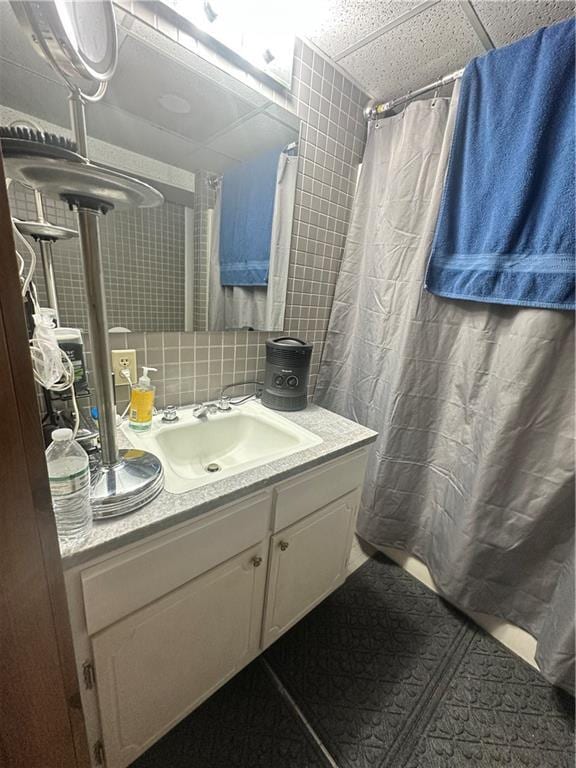 bathroom with curtained shower, backsplash, a paneled ceiling, and vanity