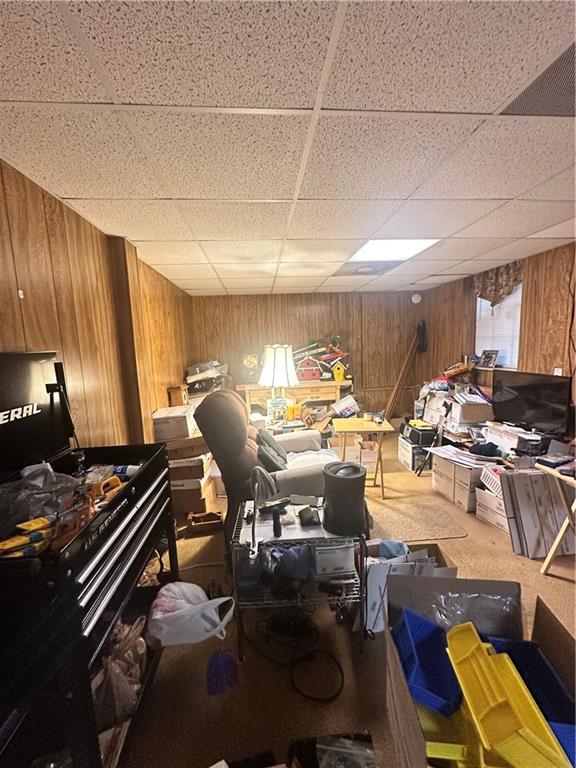 misc room with carpet, a drop ceiling, and wooden walls