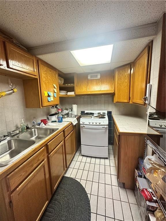 kitchen featuring sink, electric range, light tile patterned floors, and a drop ceiling